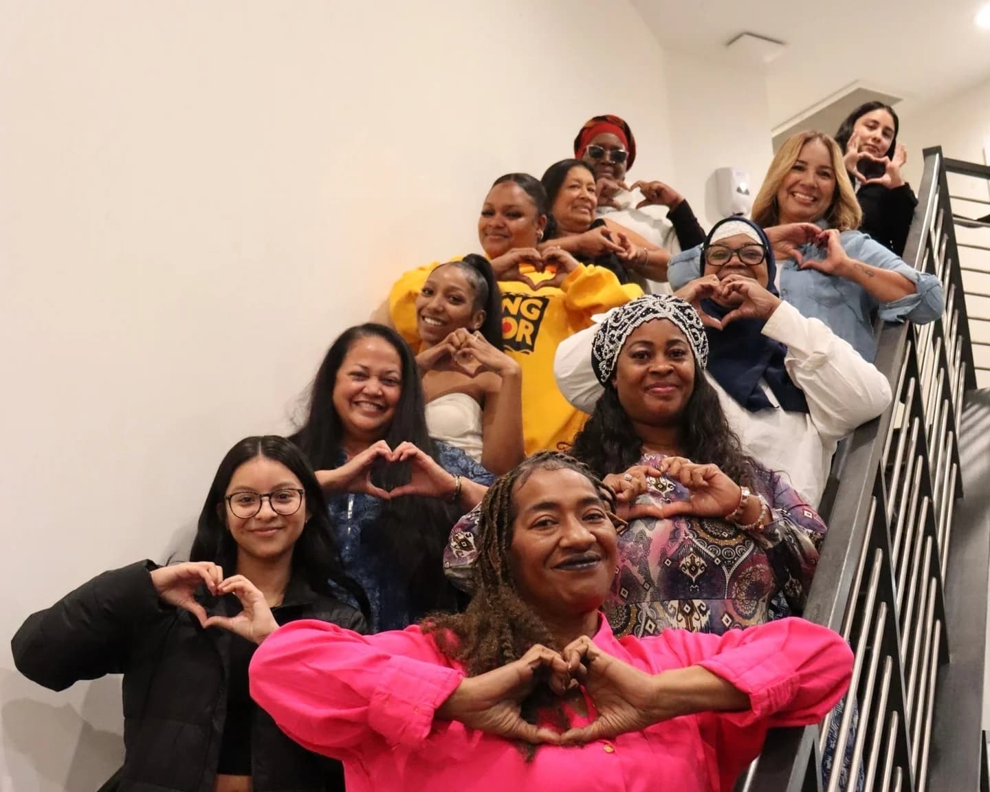 A group making heart shapes with their hands on a staircase.